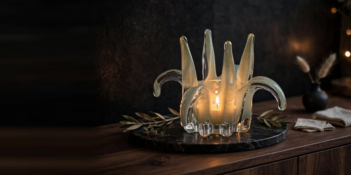 Lit opal glass candle holder on a dark marble tray against a dark wall
